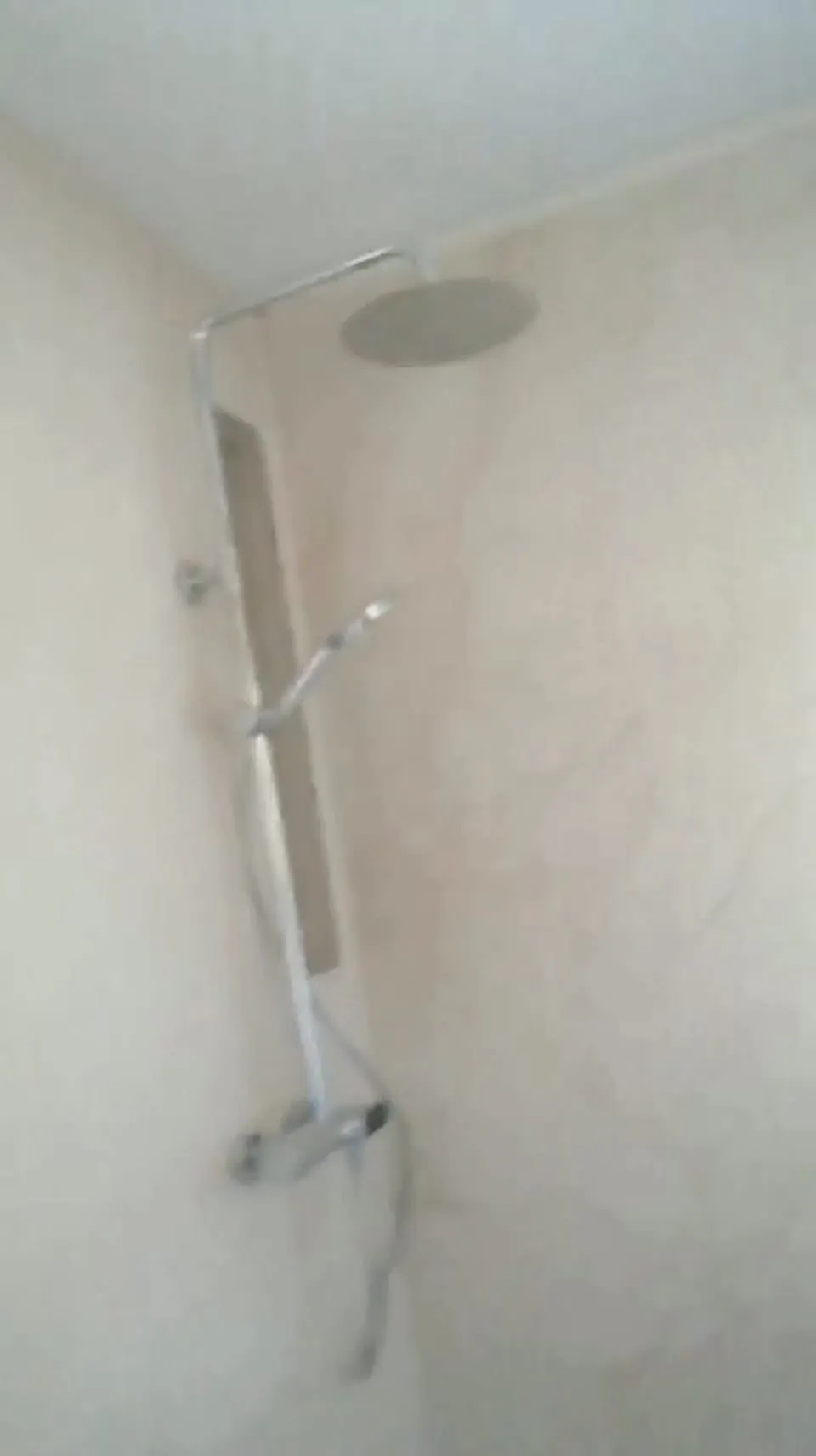 Ducha con columna de lluvia y paredes de porcelánico imitación mármol