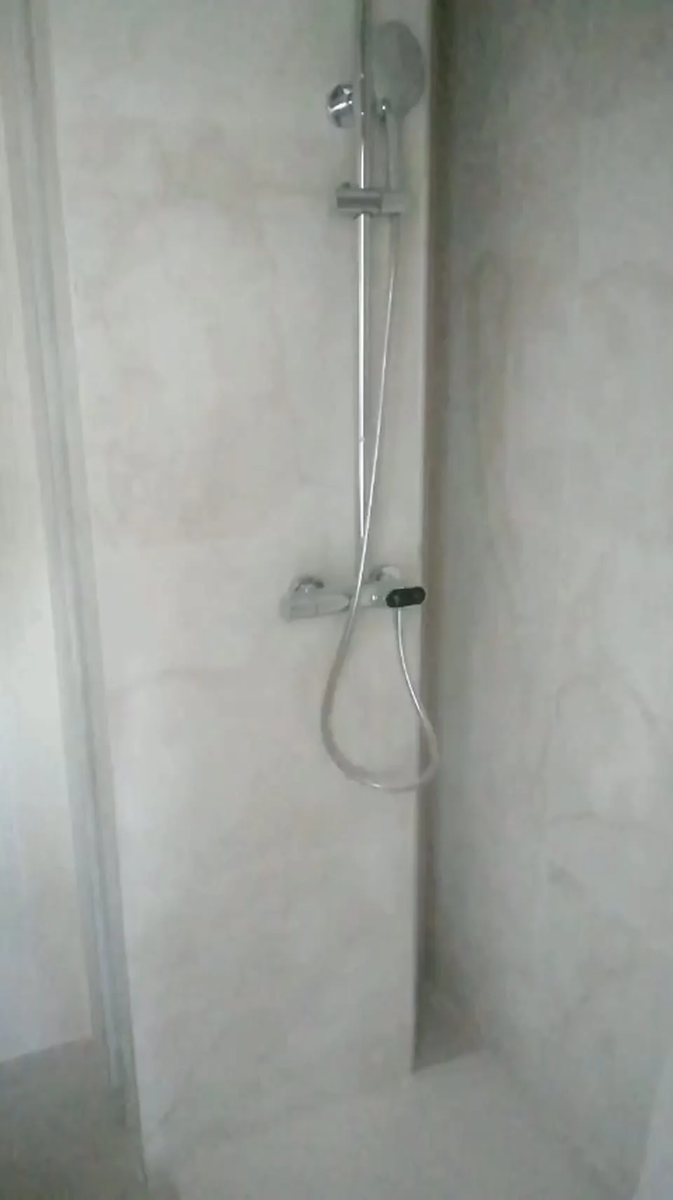 Ducha de obra con grifo termostático y paredes de porcelánico imitación mármol