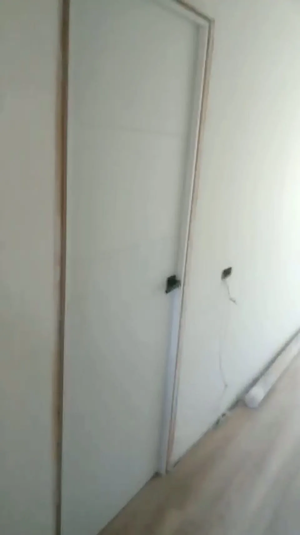 Pasillo con puerta lacada en blanco recién colocada y suelo laminado de madera